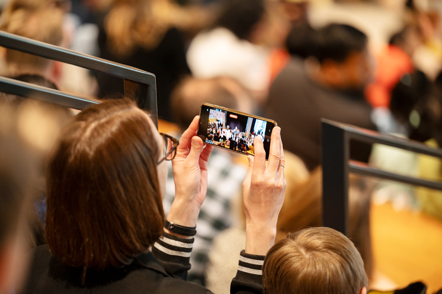 Een evenementenfoto van een mevrouw die een foto neemt van een evenement in theater Amare tijdens het Big Bang Festival. Geschoten door fotograaf Karen van Gilst.