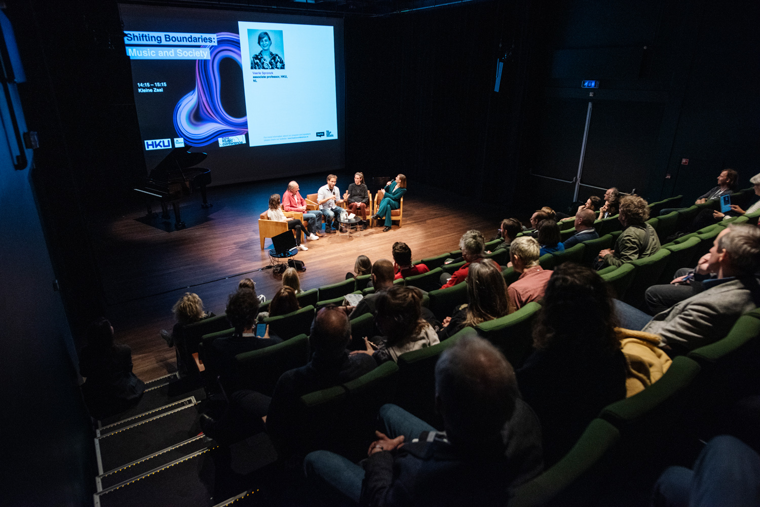 Evenementenfoto en overzichtsfoto van een panel op het toneel. Geschoten vanaf de tribune tijdens New Music New Congres in de Verkadefabriek in Den Bosch.