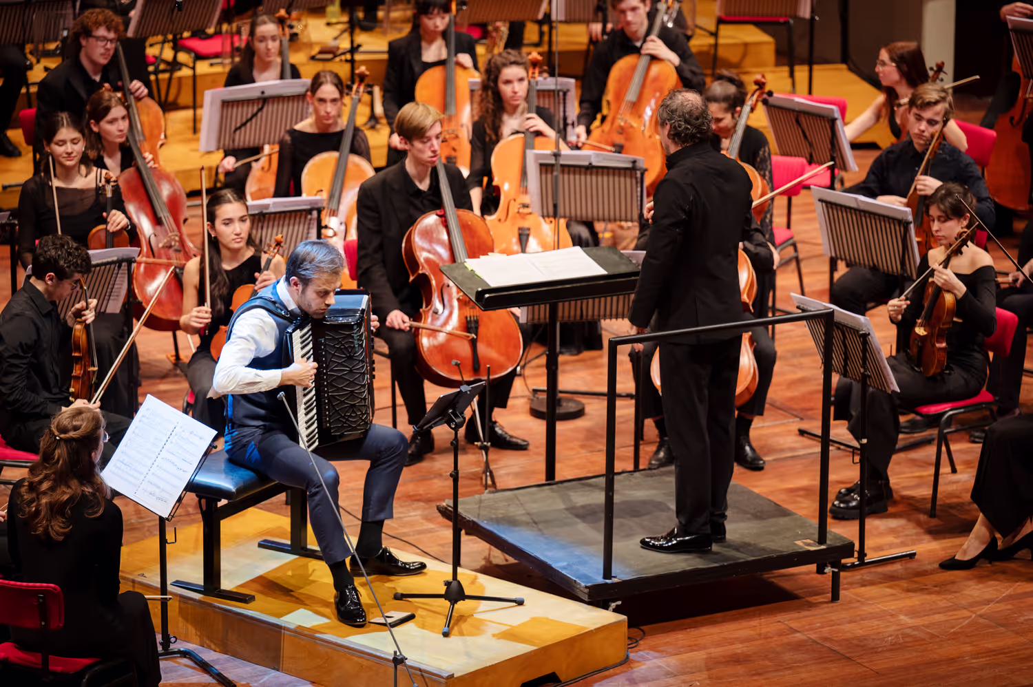 Een concertfoto van een accordeonist begeleid door een orkest. Van bovenaf geschoten in de grote zaal van Tivoli Vredenburg. Door fotograaf Karen van Gilst.