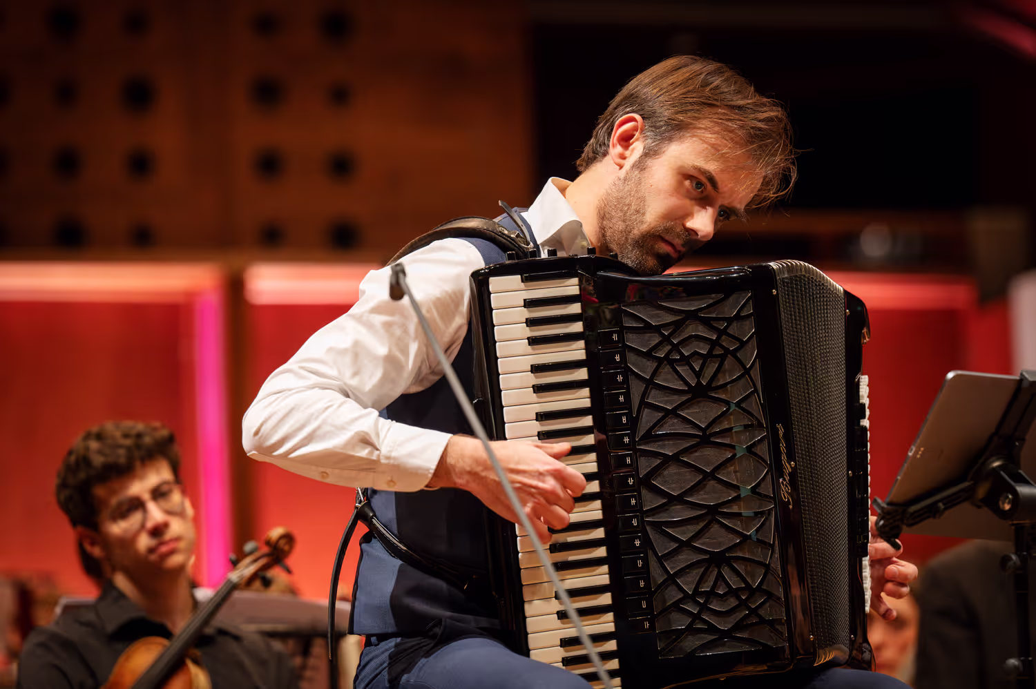 Een close-up foto van een accordeonist tijdens zijn optreden in een concertzaal. Door fotograaf Karen van Gilst.
